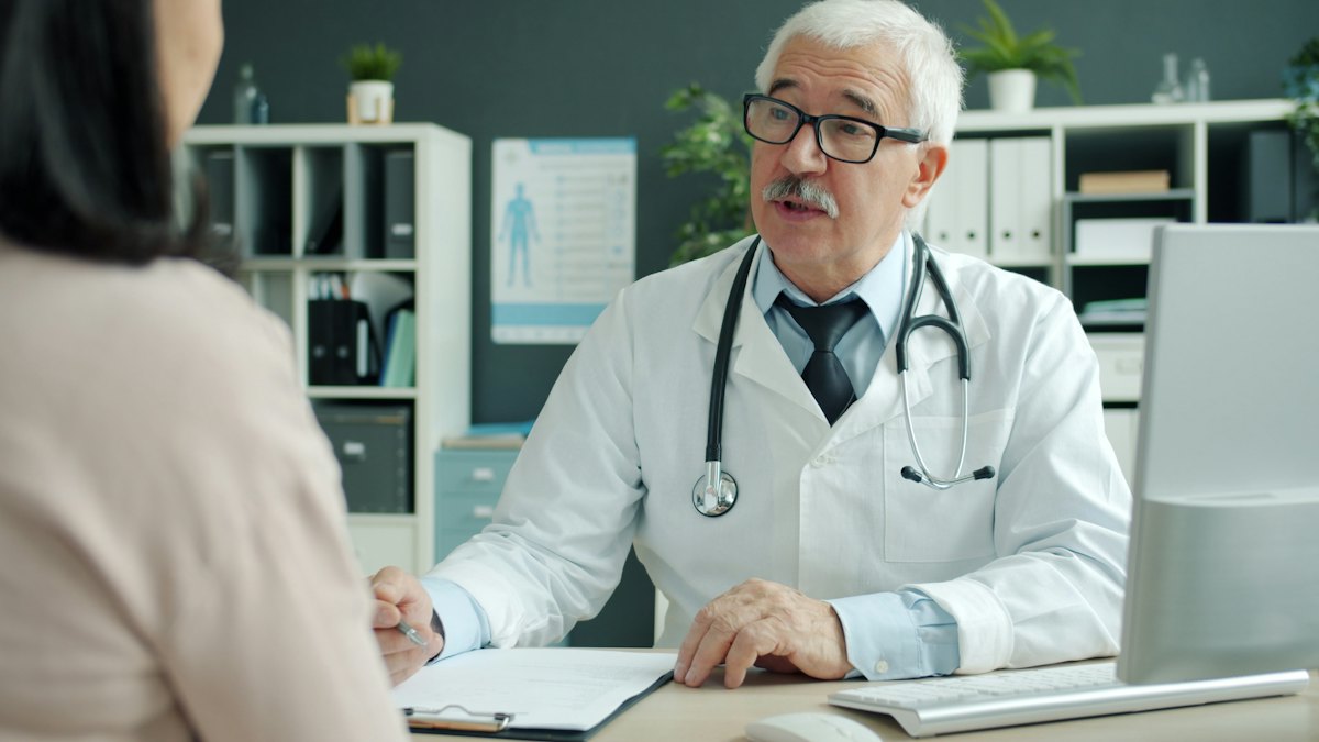 A doctor talking with a patient across a desk in an office